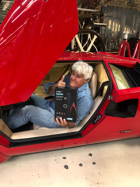 Jay Leno sitting in a sports car with the CTEK CS FREE